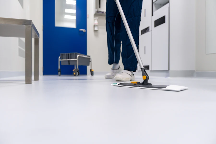 Cleaner mopping the floor of a bright institutional corridor