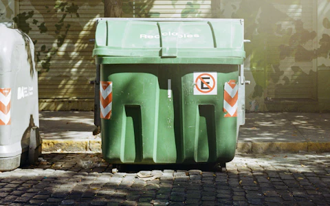 Large green four-wheeled waste container on a street