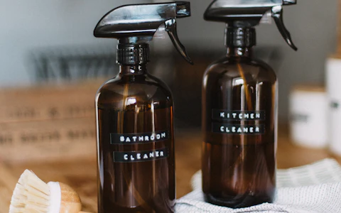 Two refillable amber glass spray bottles labelled bathroom and kitchen cleaner