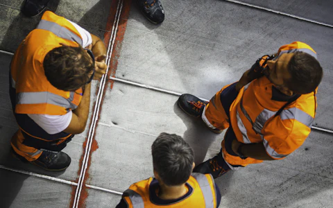Workers in orange high-visibility vests seen from above
