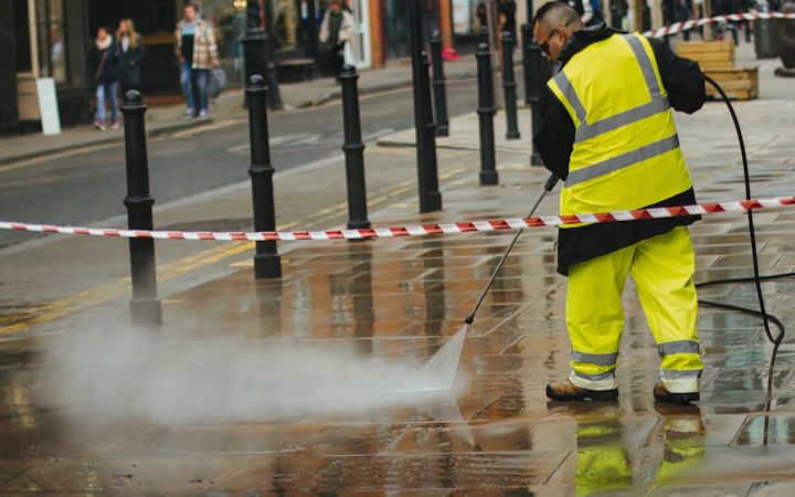 Operative in high-visibility clothing using a pressure washer
